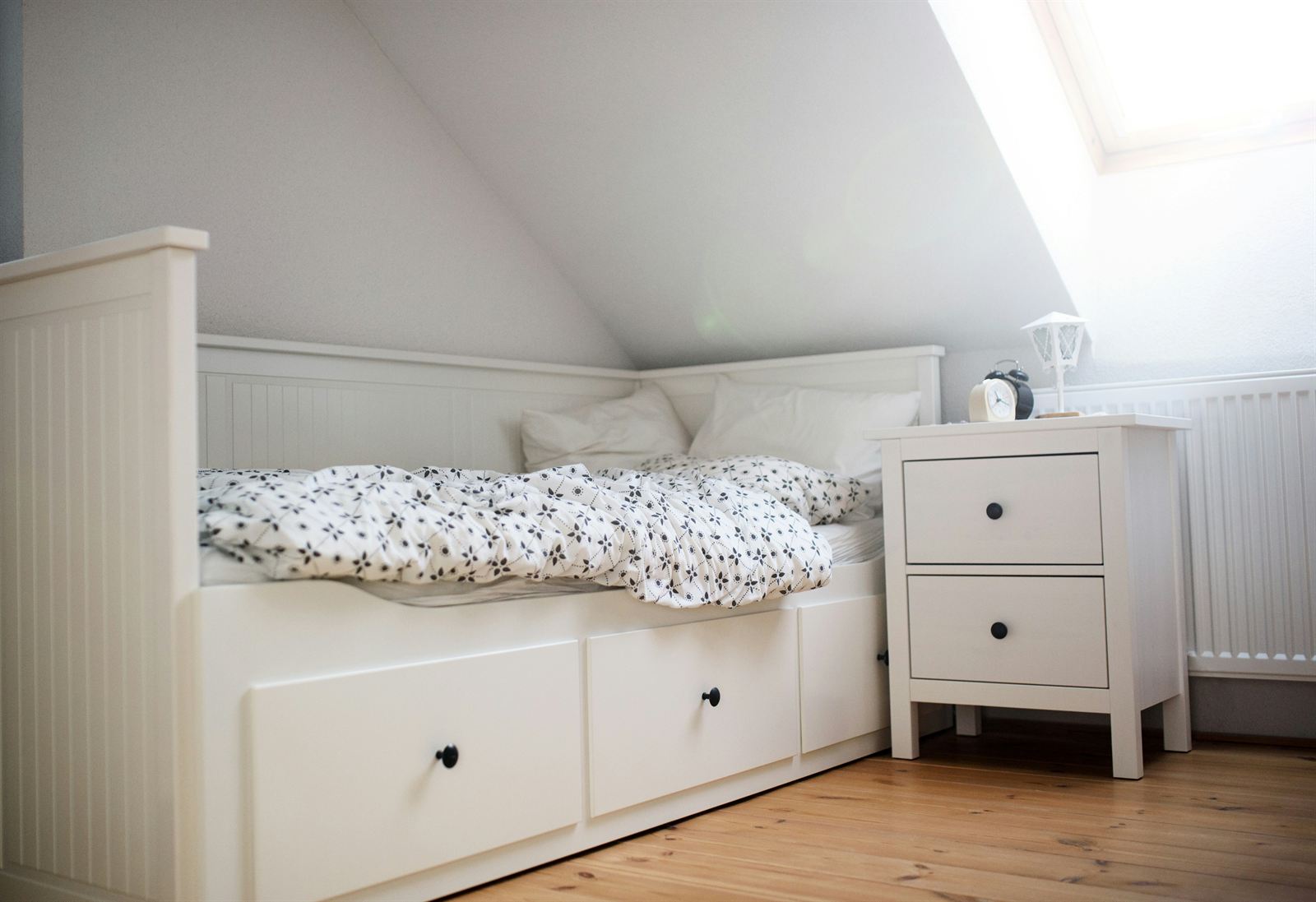Small attic bedroom with built-in under-bed storage drawers and a compact nightstand for space-saving bedroom organization. Small attic bedroom with built-in under-bed storage drawers and a compact nightstand for space-saving bedroom organization.